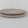 Two stacked Sandstone beige speckled stoneware dinner plates with raised rims and minimalist design