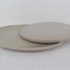 Sandstone stoneware plates showing a glossy beige speckled surface and contrasting matte underside