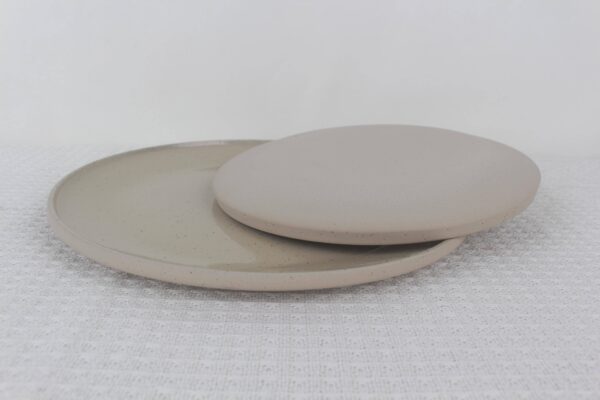 Sandstone stoneware plates showing a glossy beige speckled surface and contrasting matte underside