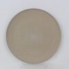 Top view of a round Sandstone stoneware dinner plate with beige glaze, fine black speckles and raised rim