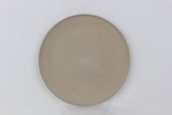 Top view of a round Sandstone stoneware dinner plate with beige glaze, fine black speckles and raised rim