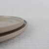 Close-up of stacked Sandstone stoneware plates showing beige speckled glaze and smooth raised edges